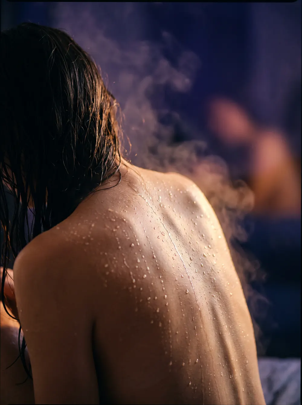 Water running down a bare back in steam